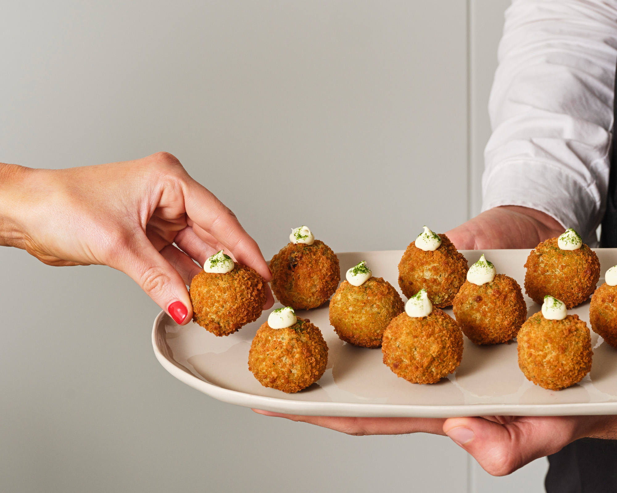 Arancini balls on a delicate platter served by a waiter for a corporate catering event